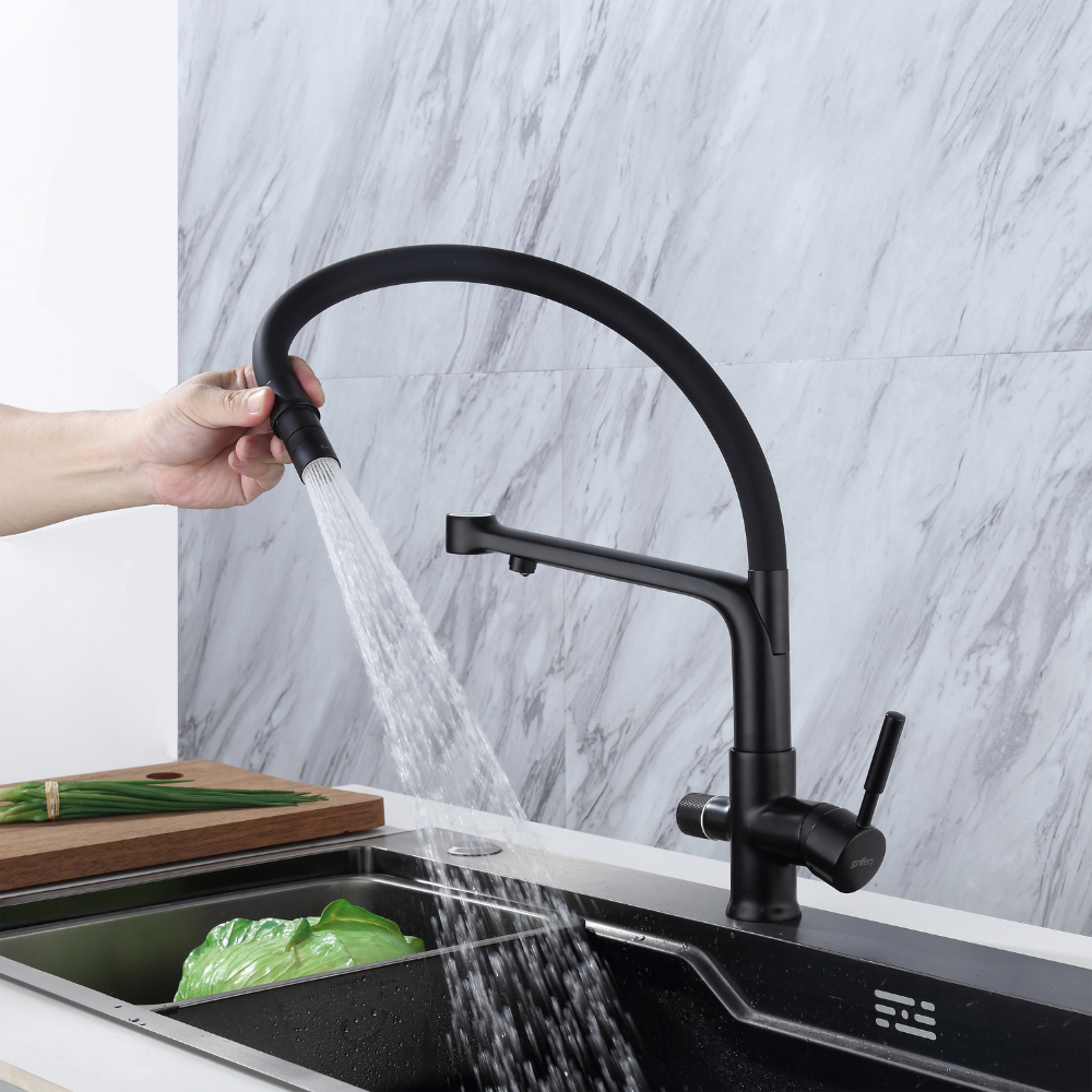 Flexible 3-way kitchen tap in use with pull-down spout spraying water into sink